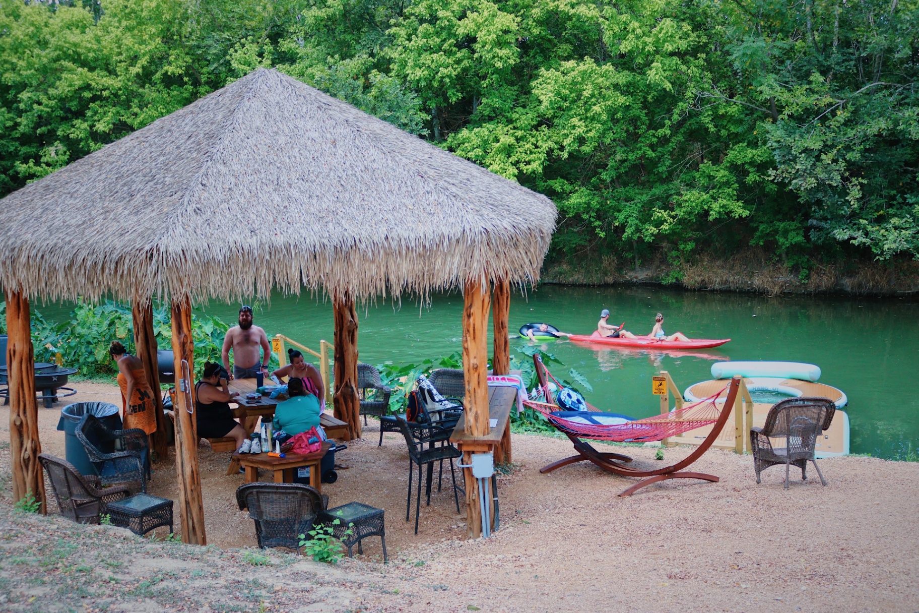 Family enjoying cabana with kayakers on creek