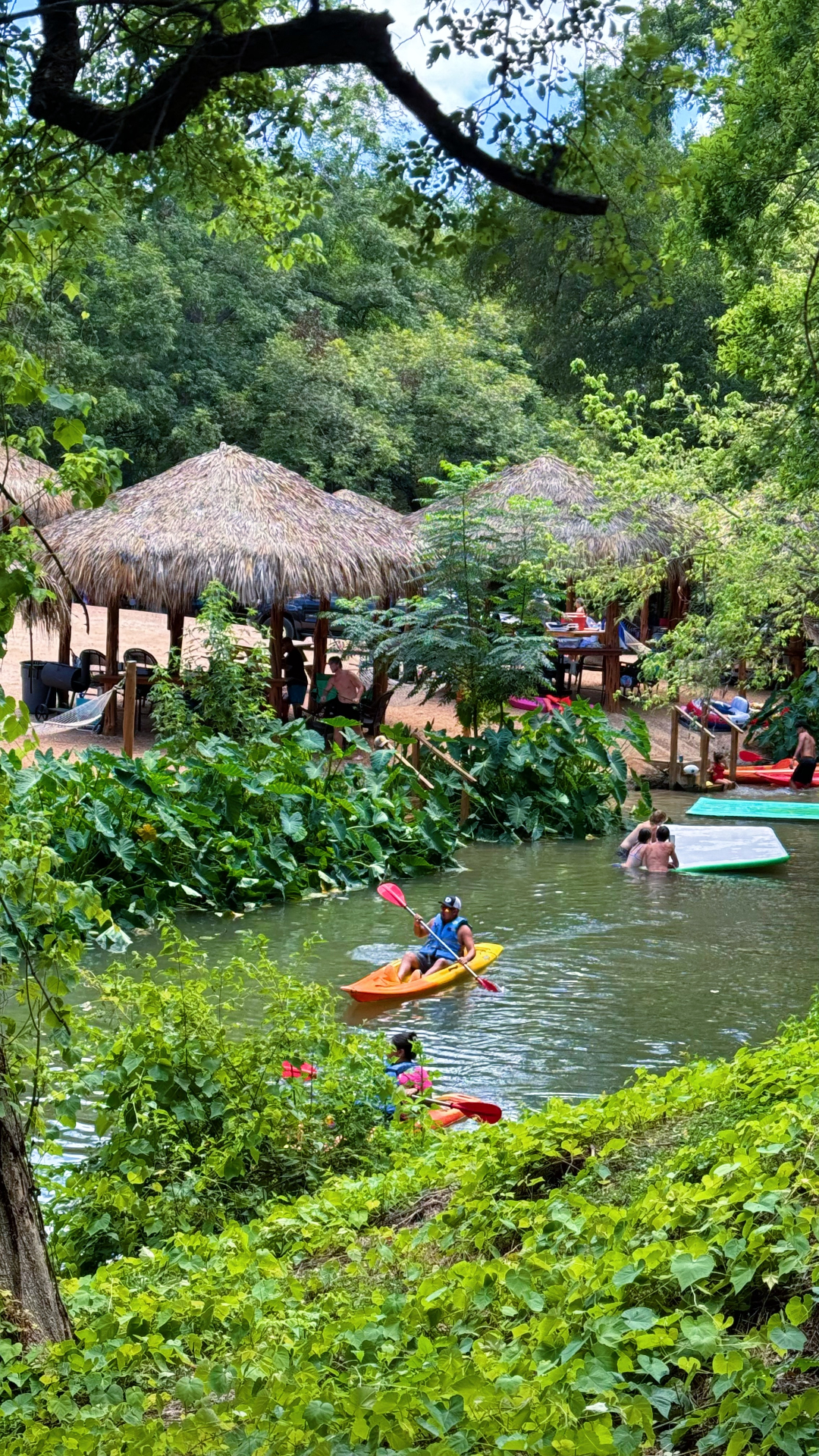 Man kayaking near tiki cabanas
